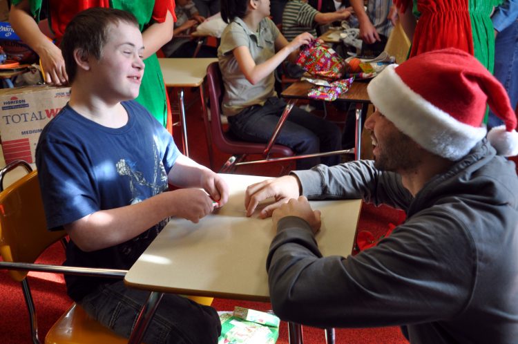 teacher wearing a Santa Claus hat working with a young student