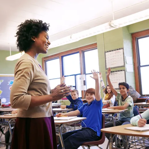 Teacher sitting in front of a classroom, talking to a group of students