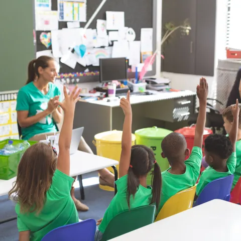 Teacher sitting in front of a classroom, talking to a group of students