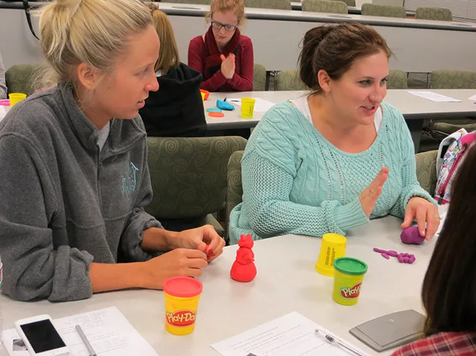 adult students at a table with play dough